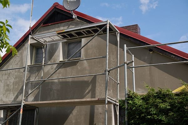 Na tym etapie ocieplania, po zatopieniu siatki, dom należy zagruntować podkładową masą tynkarską.