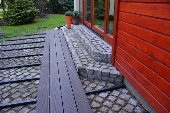 Rozpoczynamy składanie desek, zachowując odpowiednie odstępy między nimi – 5 mm przy szerokości i 10 mm na długości. Łączenie desek należy wykonać na przemian z minimalnym 50 cm przesunięciem.
