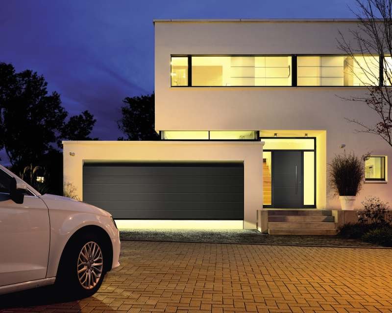 Brama garażowa i drzwi zewnętrzne tworzą spójną całość zarówno jeśli chodzi o kolorystykę, jak i wzór przetłoczeń