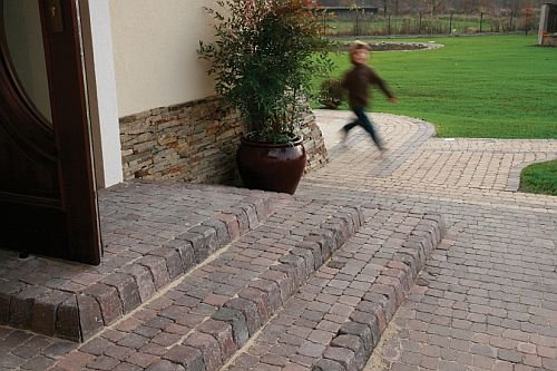 Schody tarasowe z kostki brukowej naturalnie wprowadzają w ogrodowe ścieżki