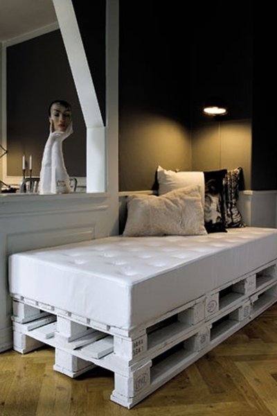 Łóżko jednoosobowe lub sofa wykonane z palet elegancko pomalowanych na biało