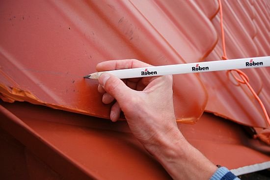 Dekarz zaznacza miejsce ciecia ołówkiem - samo cięcie najlepiej wykonać poza połacią.