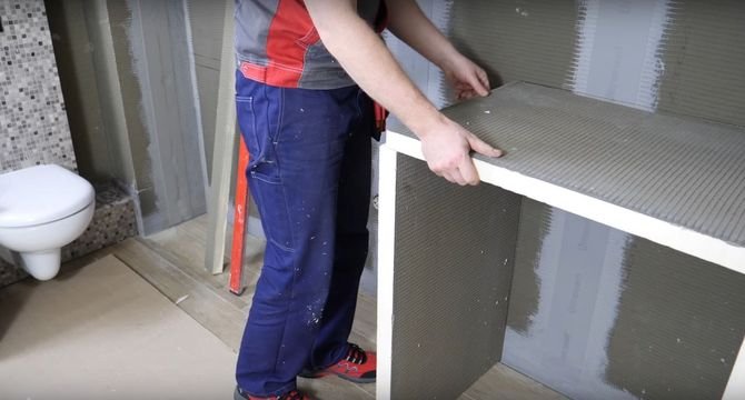 Montaż zabudowy dla pralki zacznij od stworzenia podparcia dla blatu. Przed klejeniem upewnij się, że pomiędzy płytą a ścianą zachowany jest kąt 90°. Następnie nałóż na podłogę klej z uszczelniaczem i nasuń płyty, które będą pełnić rolę nóżek.