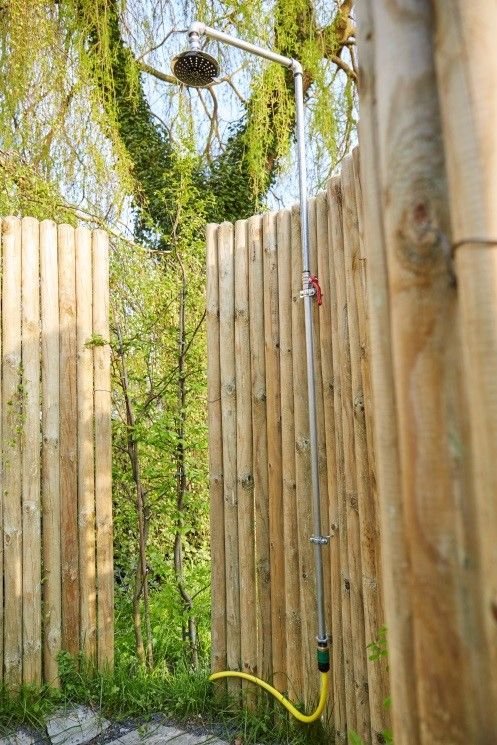 Doprowadź wodę do prysznica. Przy użyciu wiertarko-wkrętarki przykręć uchwyt prysznica do jednego z pali. Podłącz do kranu wąż i odkręć wodę.