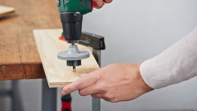 Za pomocą otwornicy, odpowiadającej wymiarom szyjek butelek i wiertarko-wkrętarki akumulatorowej Bosch EasyDrill 12-2 wywierć otwory w wyznaczonych wcześniej miejscach.