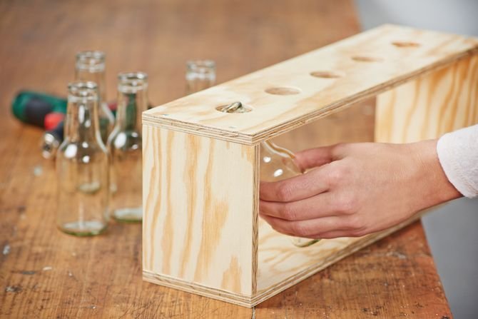 Skręć ze sobą cztery wycięte wcześniej ze sklejki lub drewna elementy. Za pomocą Bosch EasyDrill 12-2 i ośmiu wkrętów do drewna połącz te elementy tak, aby utworzyły stojak. Następnie napełnij butelki wodą, wsuń je w wycięte otwory i umieść w nich świeże.