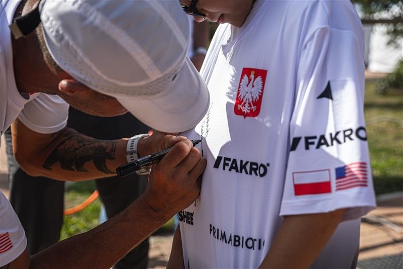 mężczyzna w czapce podpisuje koszulkę