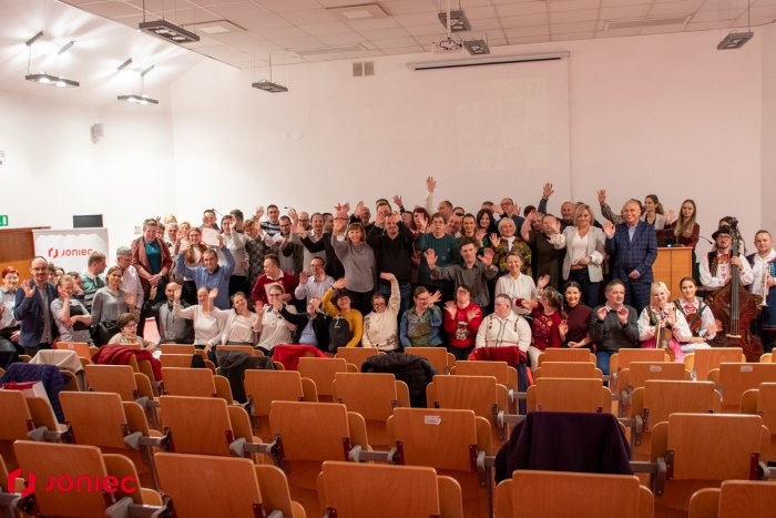 grupa osób na widowni macha do kamery