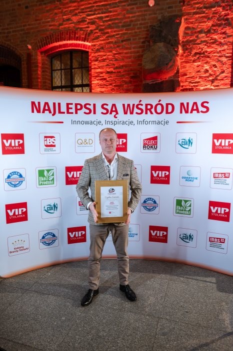 mężczyzna z dyplomem na ściance