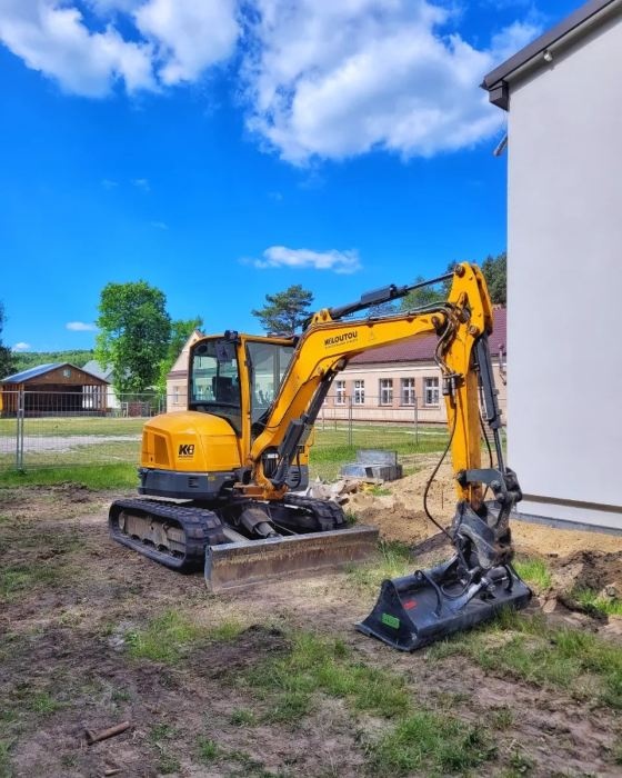 żółta koparka na trawie i silnie niebieskie niebo