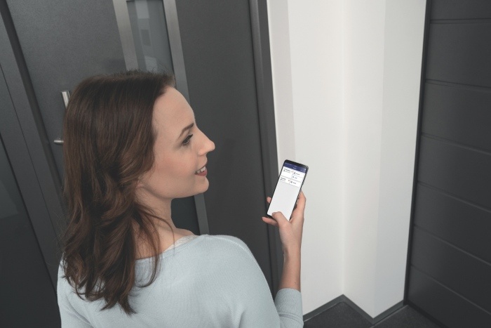 kobieta otwiera drzwi przy pomocy aplikacji w telefonie